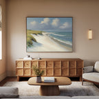 A cozy living room features a wooden coffee table, textured sideboard, cream sofa, and a large Dune Whispers Canvas Art - Horizontal on the wall. Soft lighting and neutral tones create a calm, inviting atmosphere.