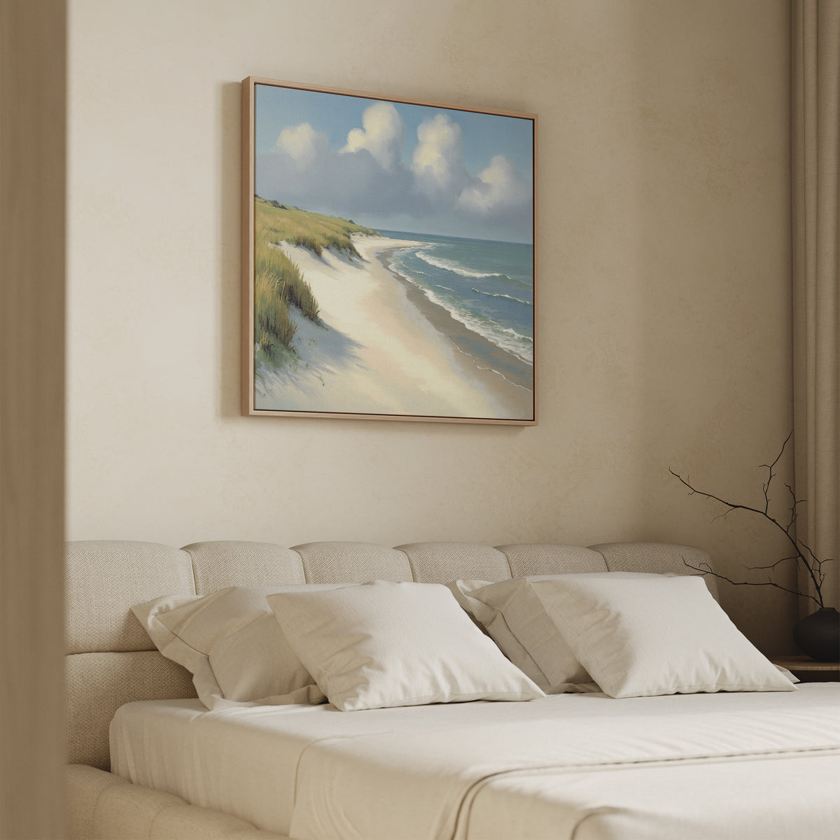 A cozy bedroom features a cream bed with white pillows and a soft headboard. Above, the "Dune Whispers Canvas Art - Square" showcases sandy beach grass, blue ocean, and a cloudy sky.