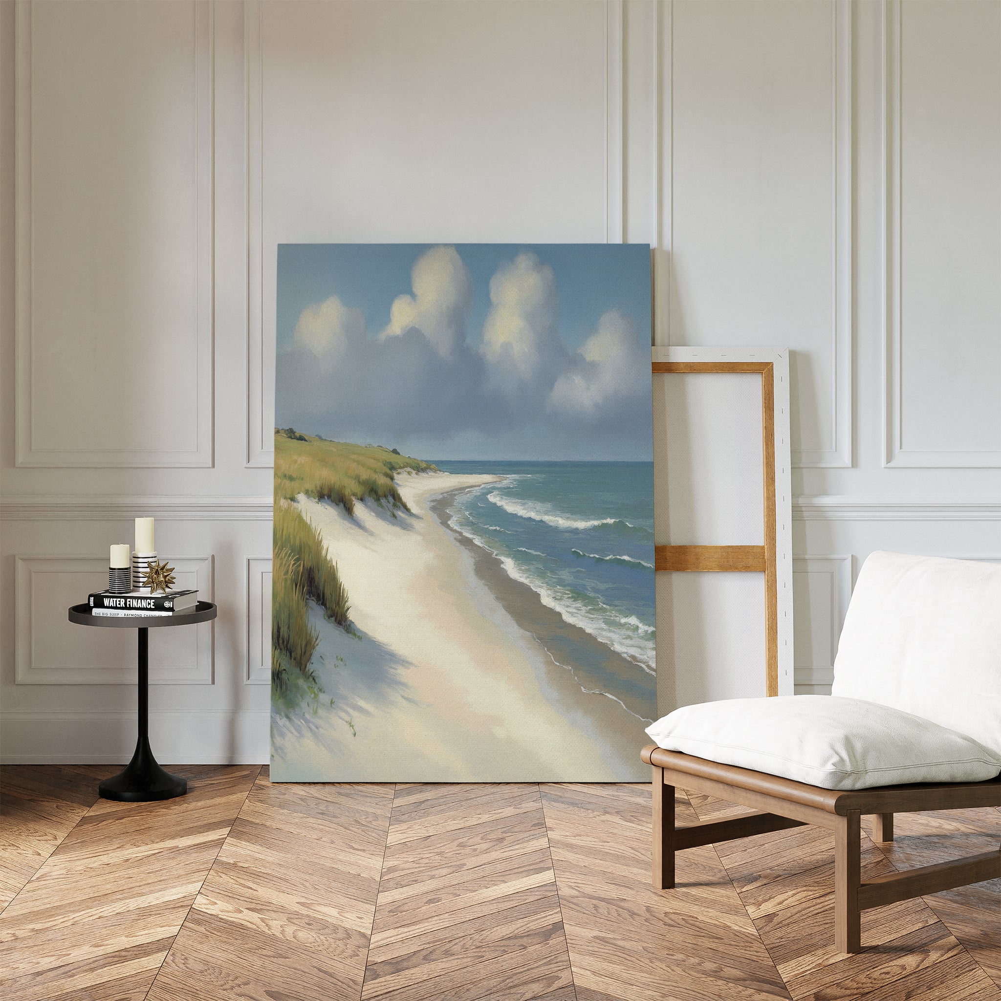 The Dune Whispers Canvas Art - Vertical leans against a white-paneled wall in a bright room, accompanied by a cushioned chair, a round table with candles, and an empty frame on the wooden floor.