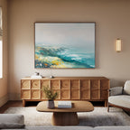 A modern living room featuring the Emerald Cliffs Canvas Art - Horizontal, a light wood sideboard, beige walls, wooden coffee table, vase with flowers, and a beige sofa for a calm, cozy atmosphere.