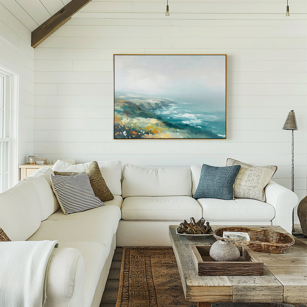A bright, airy living room with white shiplap walls, a large white sectional sofa and rustic wooden coffee table is accented by assorted pillows and the Emerald Cliffs Canvas Art - Horizontal displayed above the sofa.