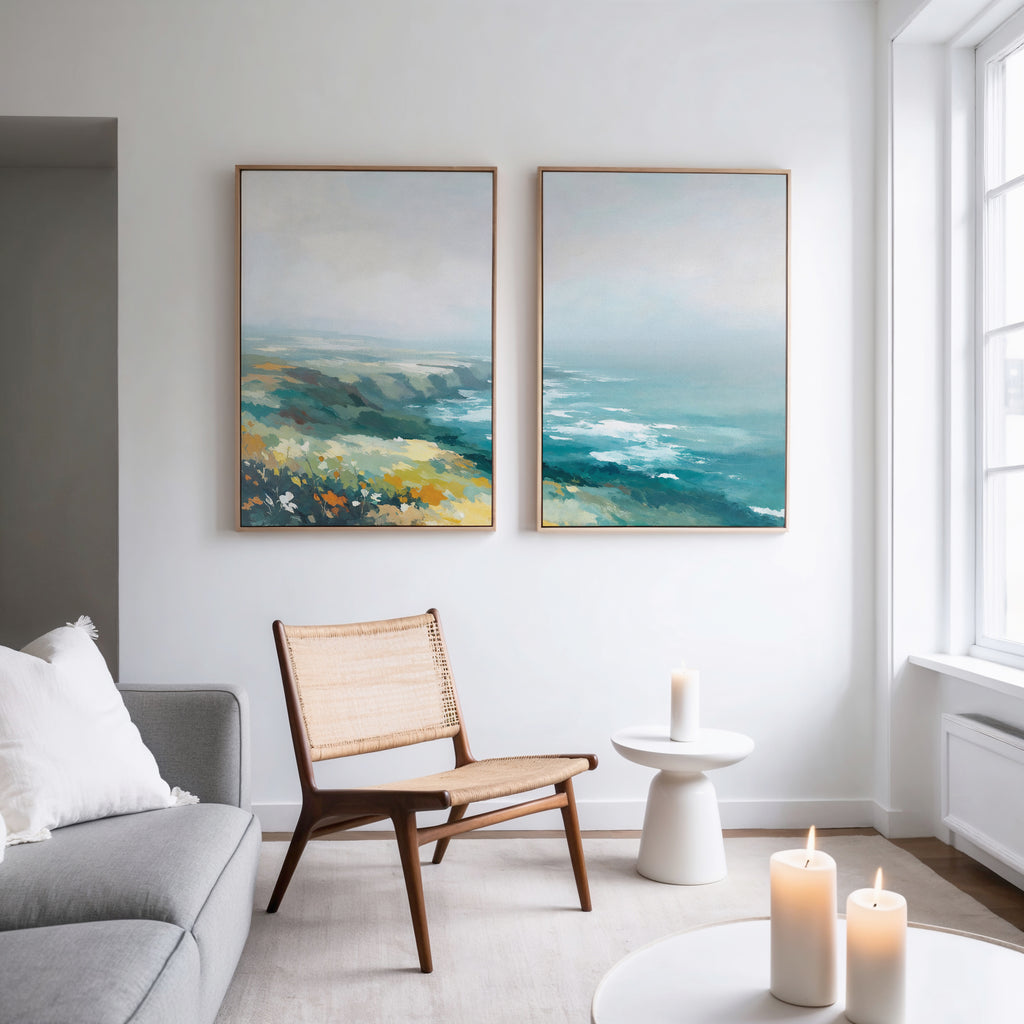 A modern living room with a gray sofa, wooden chair, and white side table glows with candles. The Emerald Cliffs - Set of 2 canvas prints add vibrant blue, green, and yellow tones to the white wall.