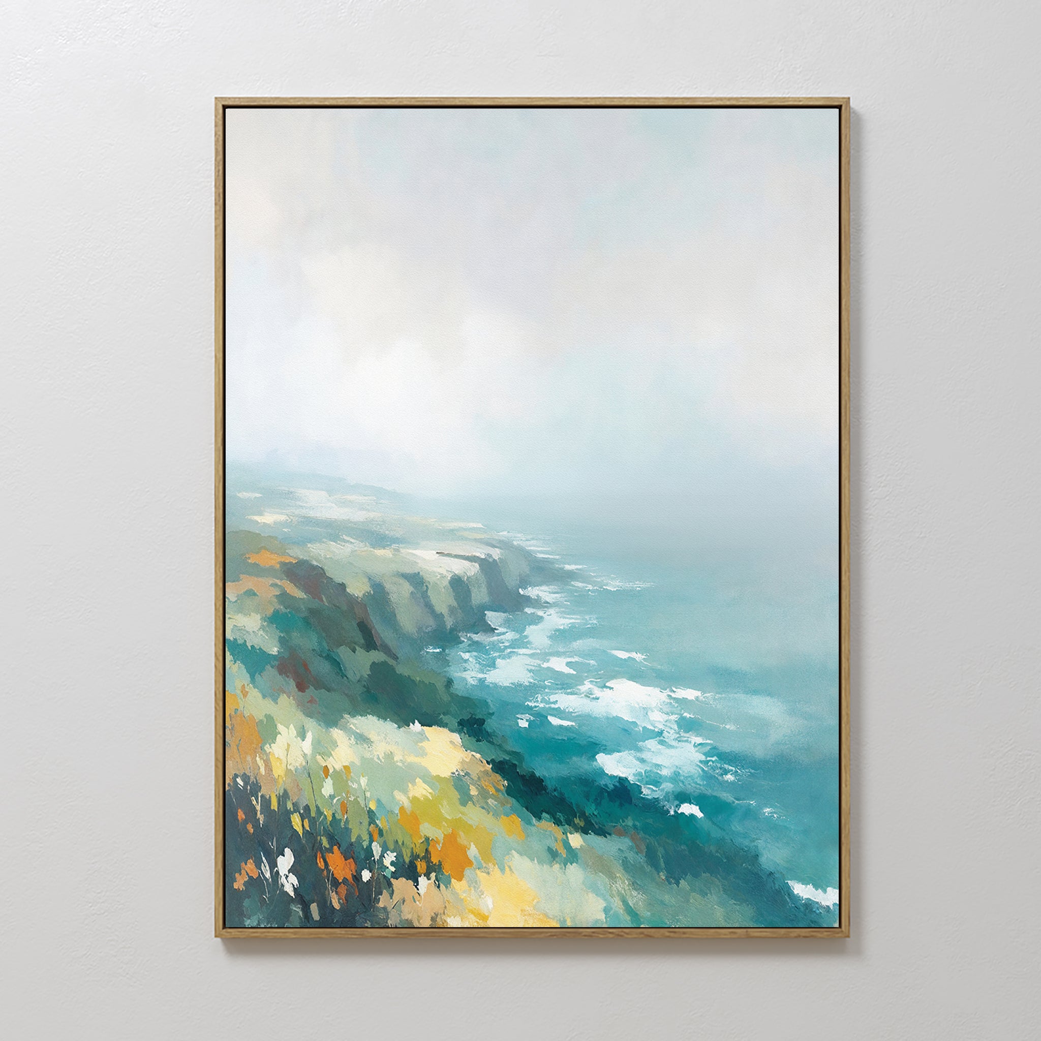 The Emerald Cliffs Canvas Art - Vertical, featuring coastal cliffs, ocean waves, and lush foliage in green, blue, and yellow under a cloudy sky, is displayed on a simple light-colored wall.
