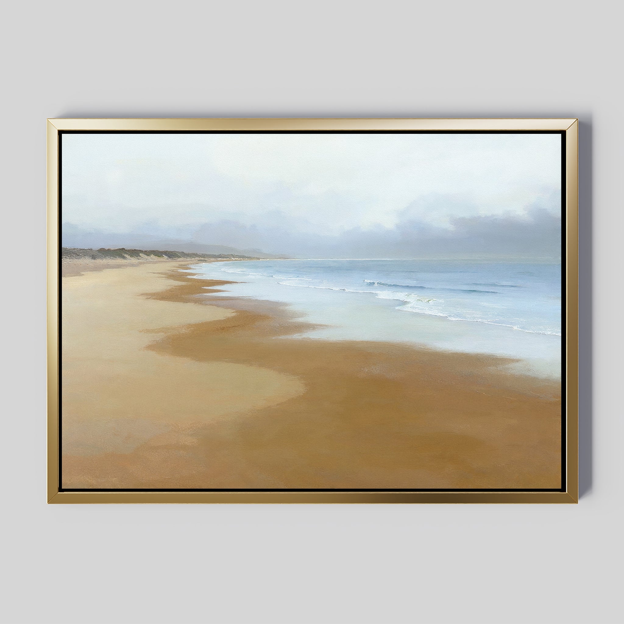 The Endless Shoreline Canvas Art - Horizontal features a serene beach with gentle waves, golden sand, and a cloudy sky, displayed in a frame against a gray wall—ideal coastal decor for creating tranquil spaces.