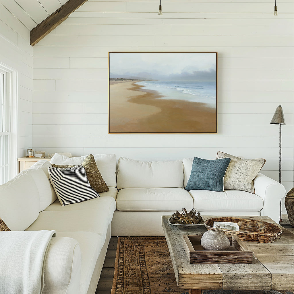 A cozy living room with white shiplap walls, a large white sectional sofa with assorted cushions, a rustic wooden coffee table, and the Endless Shoreline Canvas Art - Horizontal displayed above the sofa.