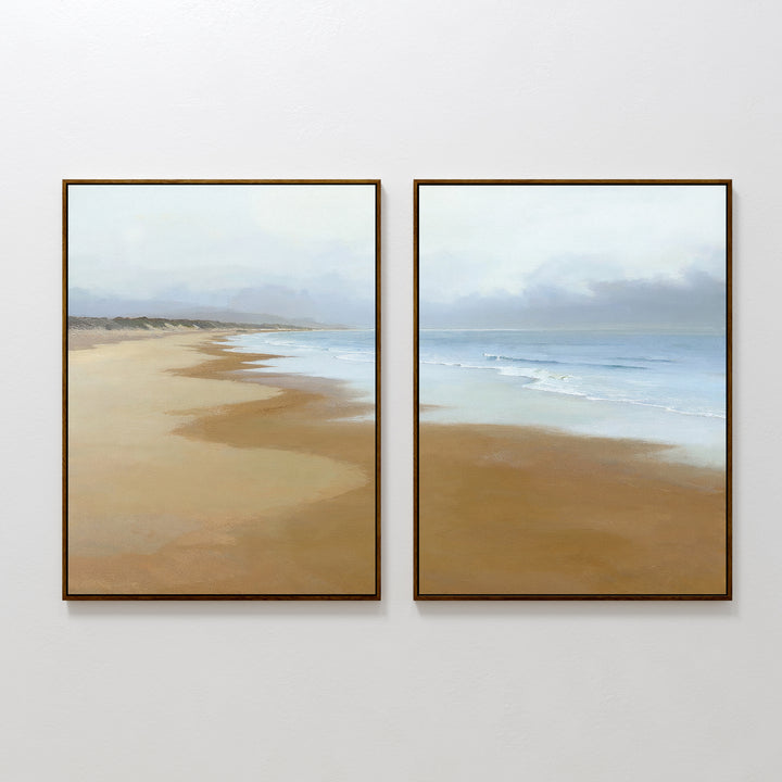 The Endless Shoreline - Set of 2 features framed canvas prints depicting serene beach scenes with golden sand, gentle waves, and a cloudy sky. This Nordic Park wall art duo adds tranquility to your space with two unique shoreline perspectives.
