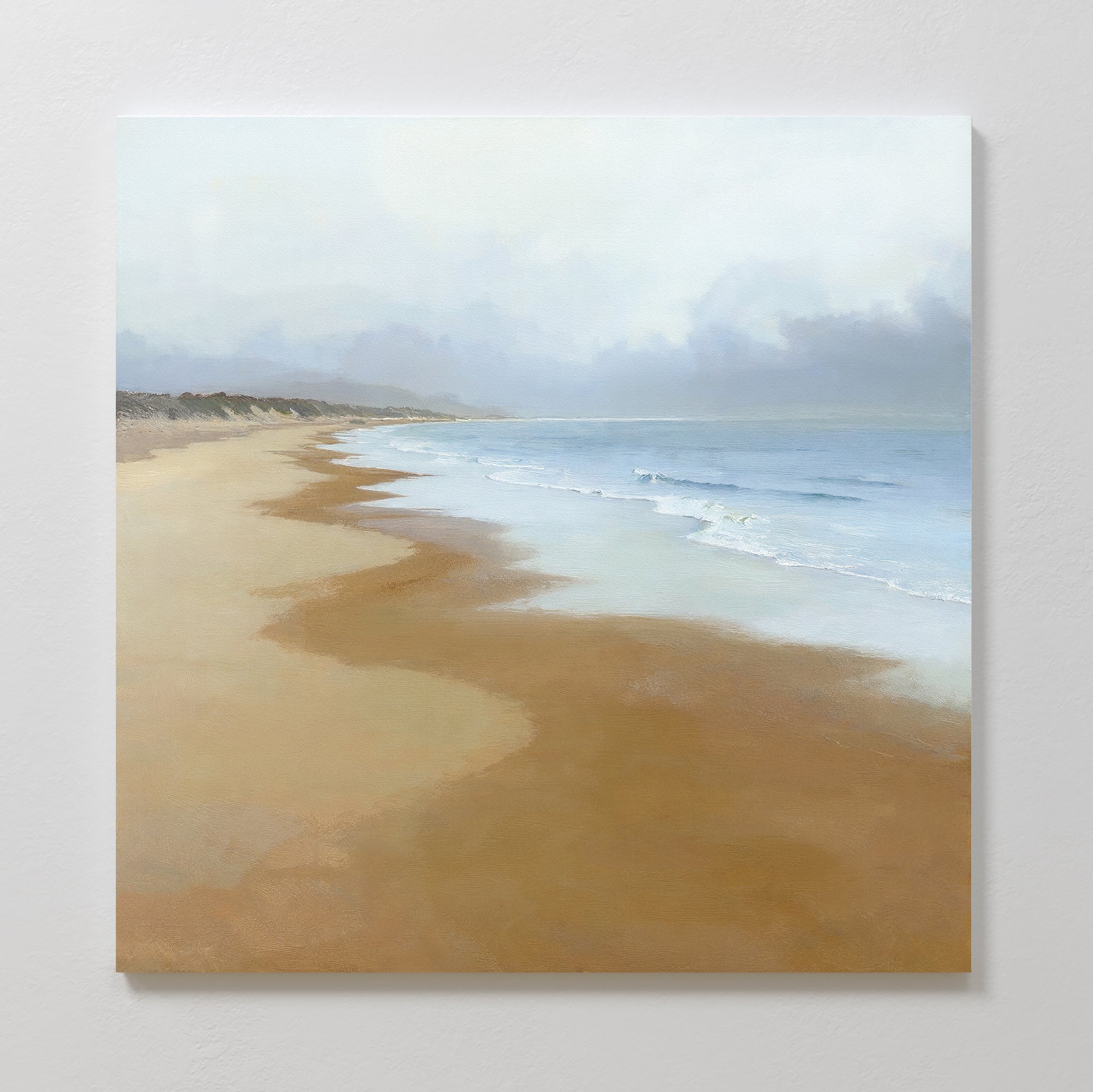 Endless Shoreline Canvas Art - Square features a calm, sandy beach with gentle waves and a cloudy sky, making it ideal coastal wall art to add a peaceful, serene touch to your home.