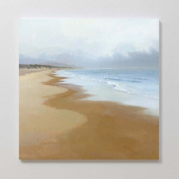 Endless Shoreline Canvas Art - Square features a calm, sandy beach with gentle waves and a cloudy sky, making it ideal coastal wall art to add a peaceful, serene touch to your home.