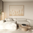 A modern living room features a beige sectional, light wood coffee table, and the Whispering Reeds Canvas Art. Sunlight streams in, enhancing the serene atmosphere and highlighting the sleek, minimalist decor.