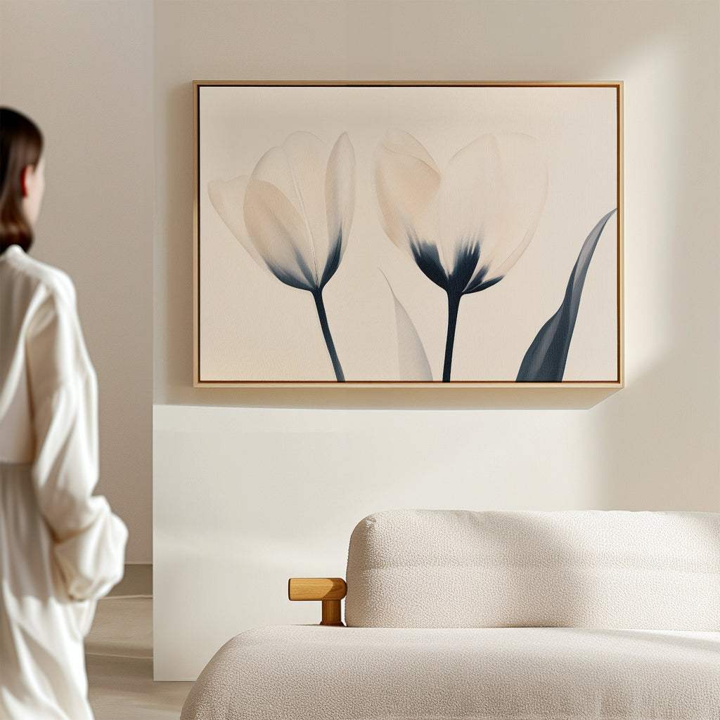 A person in a white shirt stands in a bright, modern living room, admiring the Ethereal Blooms Canvas Art - Horizontal, which displays delicate abstract flowers above a beige sofa.