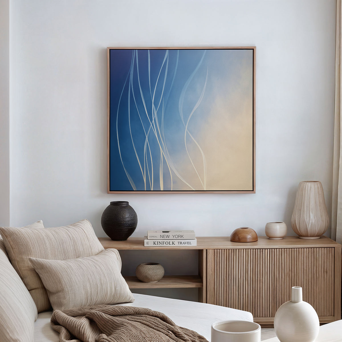 A minimalist living room with a neutral sofa, textured pillows, and a wooden sideboard styled with vases and books. Above, the Ethereal Lines Canvas Art - Square adds modern flair as sunlight filters through soft window curtains.