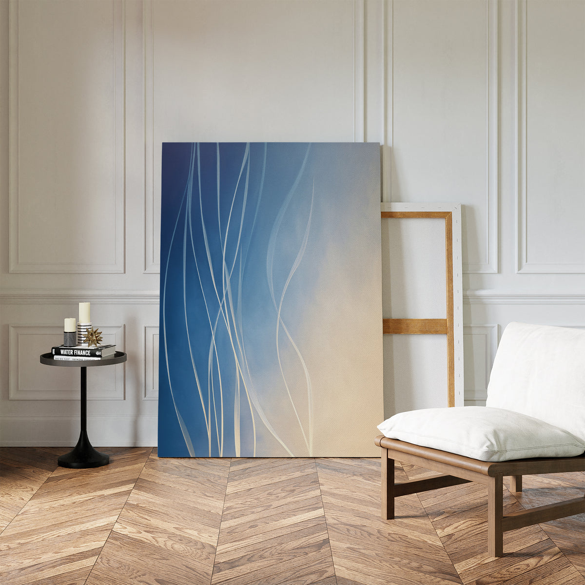 The Ethereal Lines Canvas Art - Vertical, a large abstract blue and beige painting with white lines, is styled against a white paneled wall. Nearby are a cushioned chair and black round table with books and candles on a herringbone wood floor.