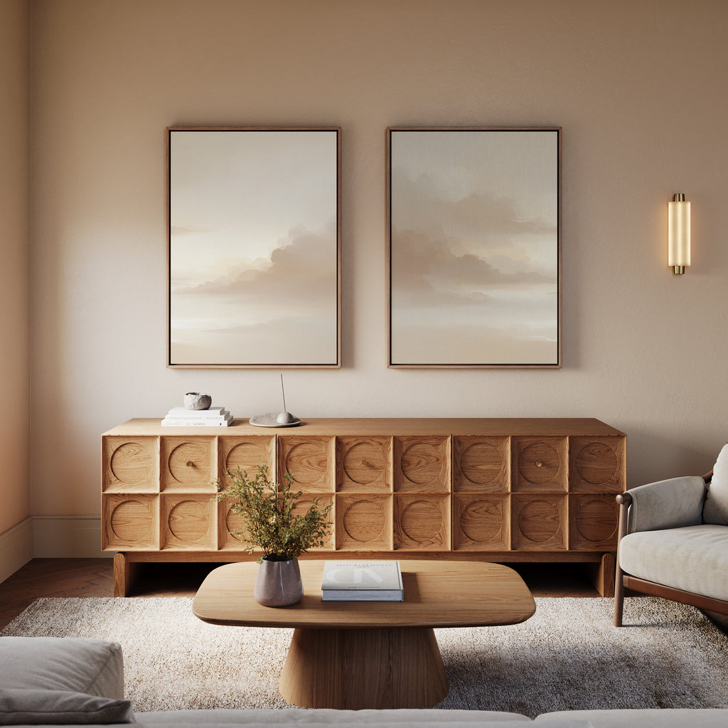 A cozy living room features a wooden sideboard, two Ethereal Veil canvas prints above it, a modern wall light, a coffee table with a vase of greenery, and a cushioned armchair for inviting decor.