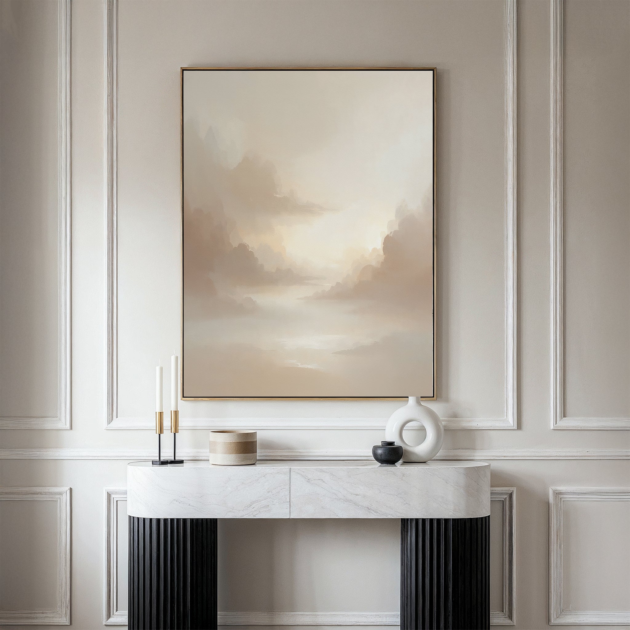 A minimalist interior features a marble console table, decor accents, and the Ethereal Veil Canvas Art - Vertical: a serene beige cloudy sky print elegantly displayed on a paneled wall.