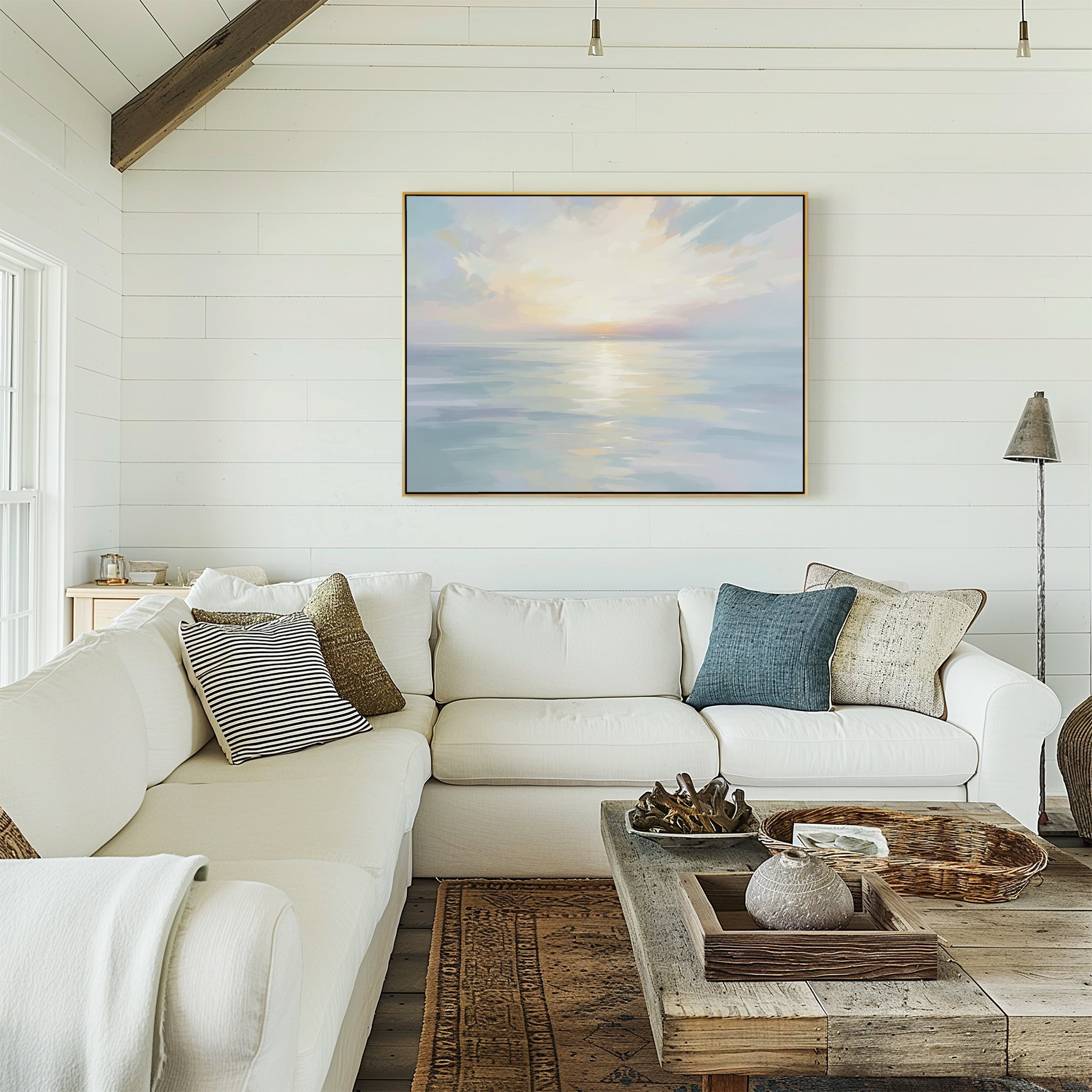 A cozy living room with a white sectional, assorted pillows, and a wooden coffee table with décor. On the white shiplap wall hangs the Ethereal Waters Canvas Art - Horizontal. Natural light fills the space from nearby windows.