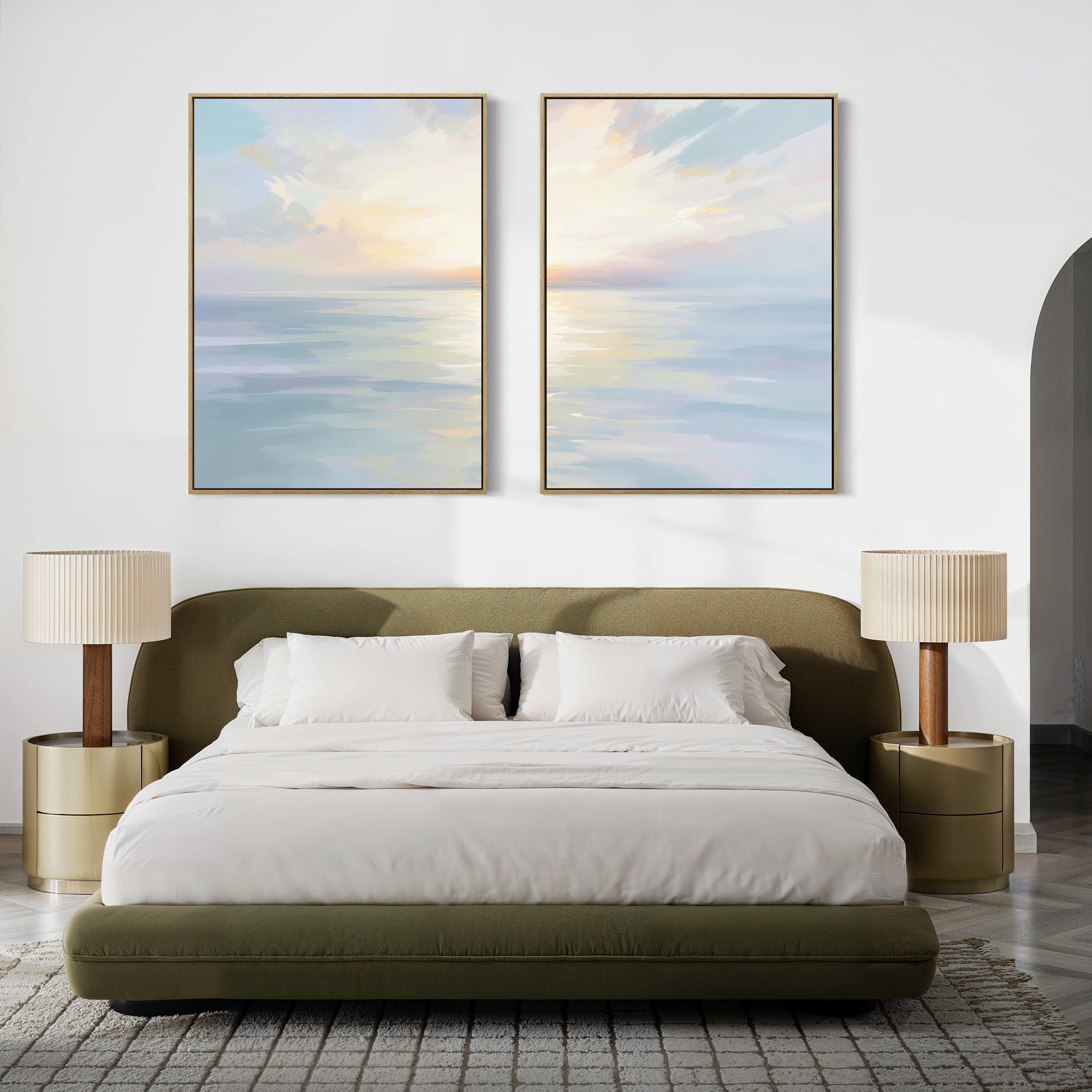 A modern bedroom with a green upholstered bed, white bedding, two gold nightstands with beige lamps, and the Ethereal Waters - Set of 2 large coastal seascape canvas prints hanging above the bed.