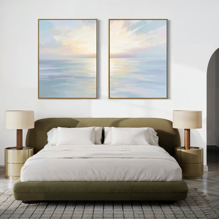 A modern bedroom with a green upholstered bed, white bedding, two gold nightstands with beige lamps, and the Ethereal Waters - Set of 2 large coastal seascape canvas prints hanging above the bed.