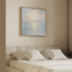 A serene bedroom features a beige bed, white pillows, and the Ethereal Waters Canvas Art - Square—a large pastel seascape—above the headboard. Natural light and minimal decor enhance the calm, peaceful atmosphere.