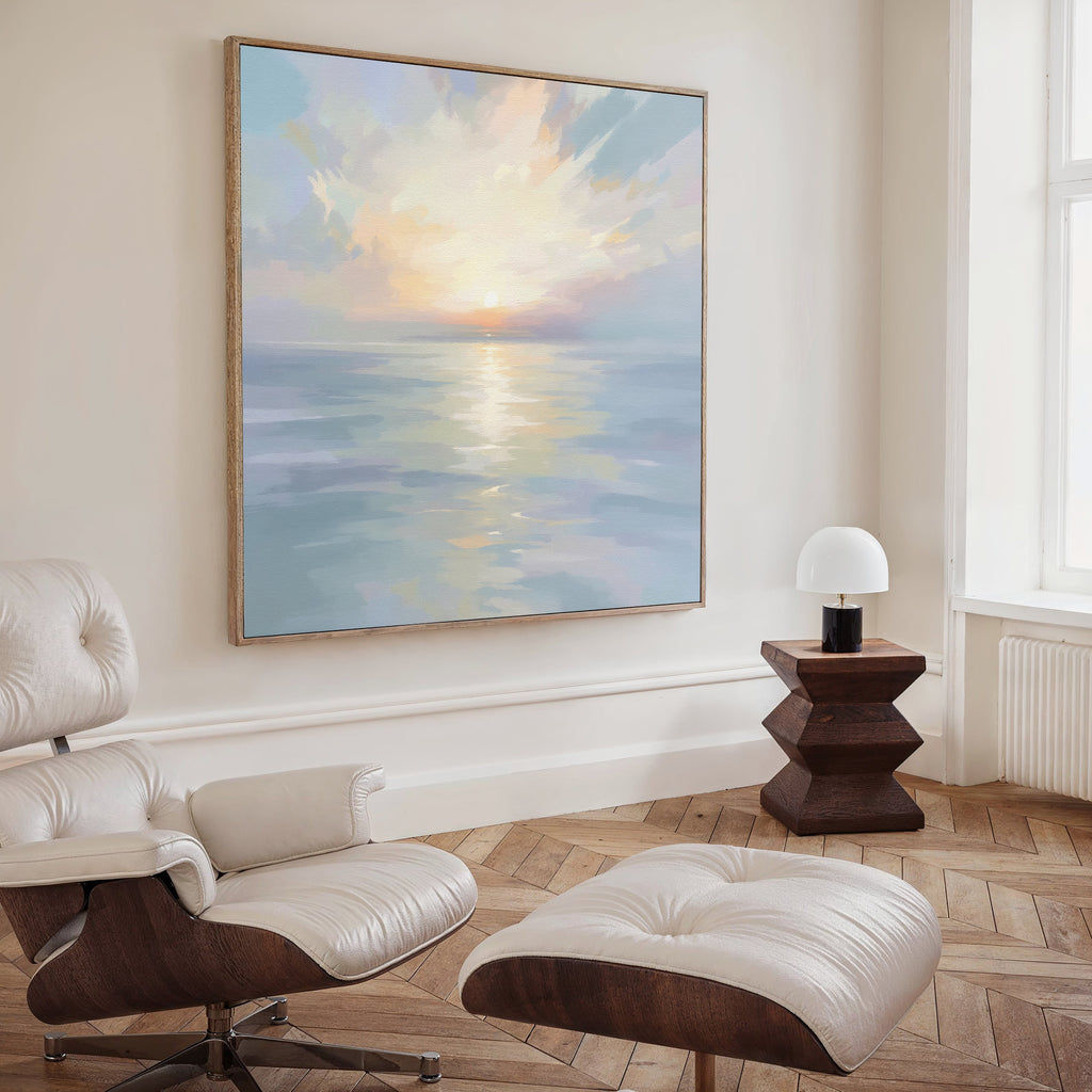 A modern living room with a white leather lounge chair and ottoman, a geometric wooden side table with a lamp, and tranquil wall art—a large Ethereal Waters Canvas Art - Square—on the wall.