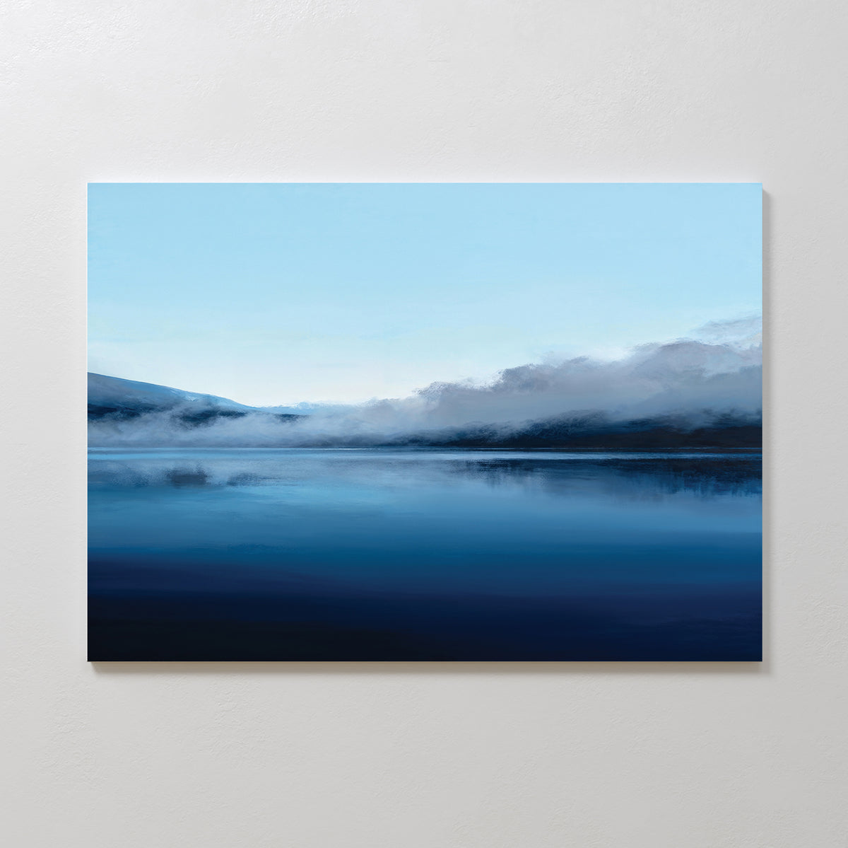The Fjord Mist Canvas Art - Horizontal features a serene landscape of a calm lake, blue skies, misty mountains, and low clouds—creating a tranquil home decor accent for any space.
