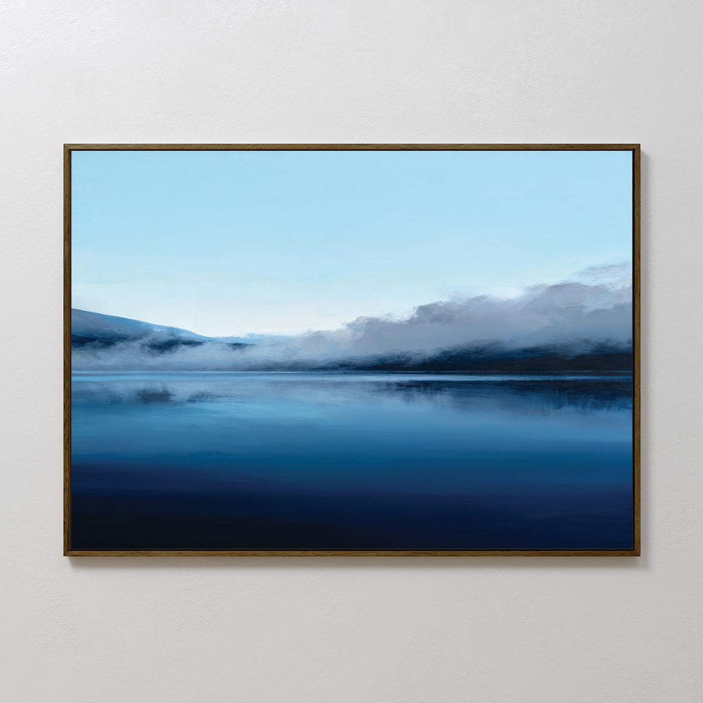 The Fjord Mist Canvas Art - Horizontal features a peaceful lake, calm blue water, misty mountains, and a pale sky—ideal for bringing serene, tranquil decor to any plain white wall.