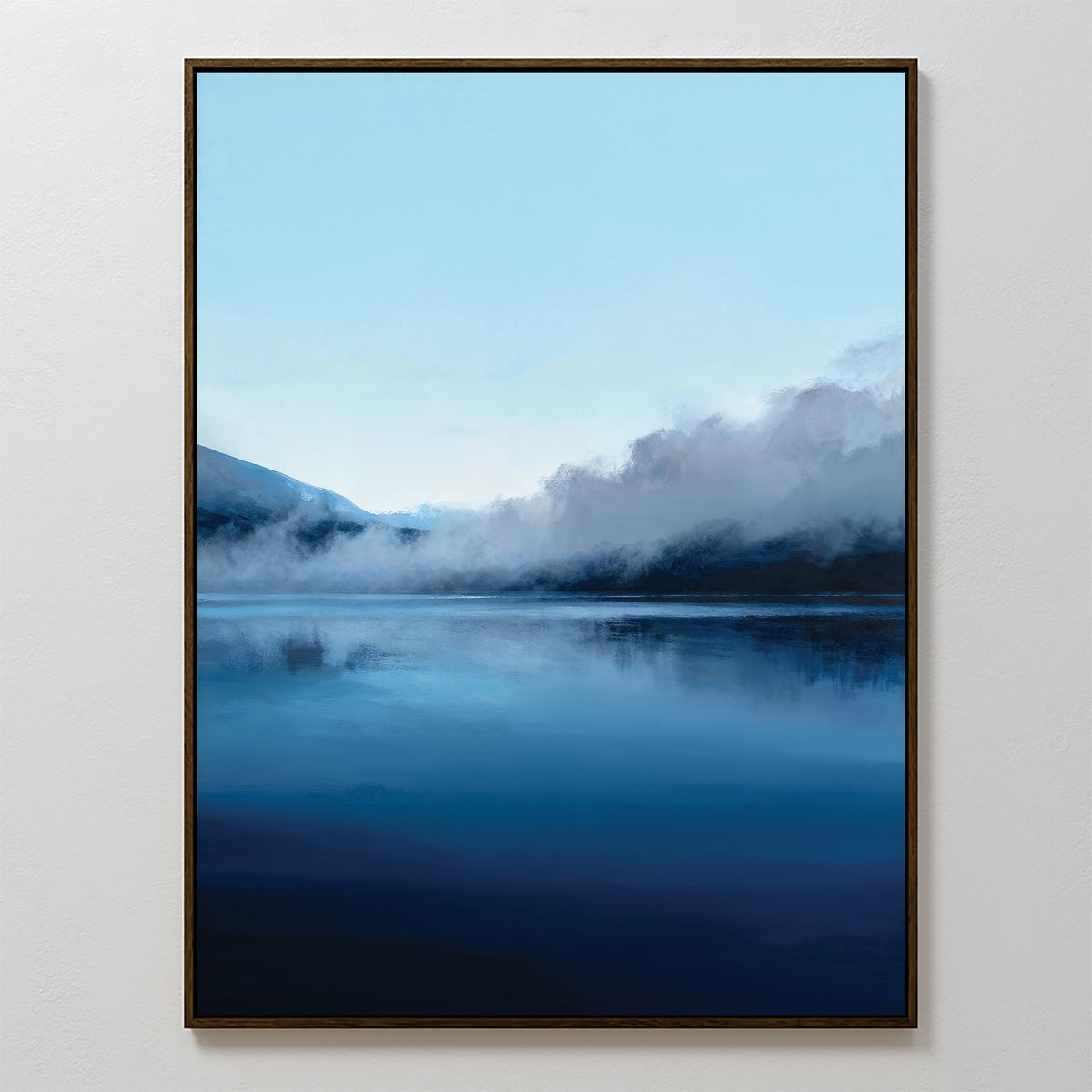 Bring calming Nordic decor to any space with the Fjord Mist Canvas Art - Vertical, featuring a serene lake reflecting blue sky and mountains, with mist drifting over water and hills in a tranquil landscape print.