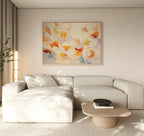 A modern living room with a light beige sectional sofa, a low wooden coffee table with a black bowl, a tall plant, and the Floating Petals Canvas Art - Horizontal adds an elegant touch with its swirling shapes and organic floating petals.