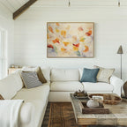 A cozy living room with white shiplap walls, a large white sectional sofa, a rustic wooden coffee table, and the Floating Petals Canvas Art - Horizontal displayed above the couch for an elegant organic touch.