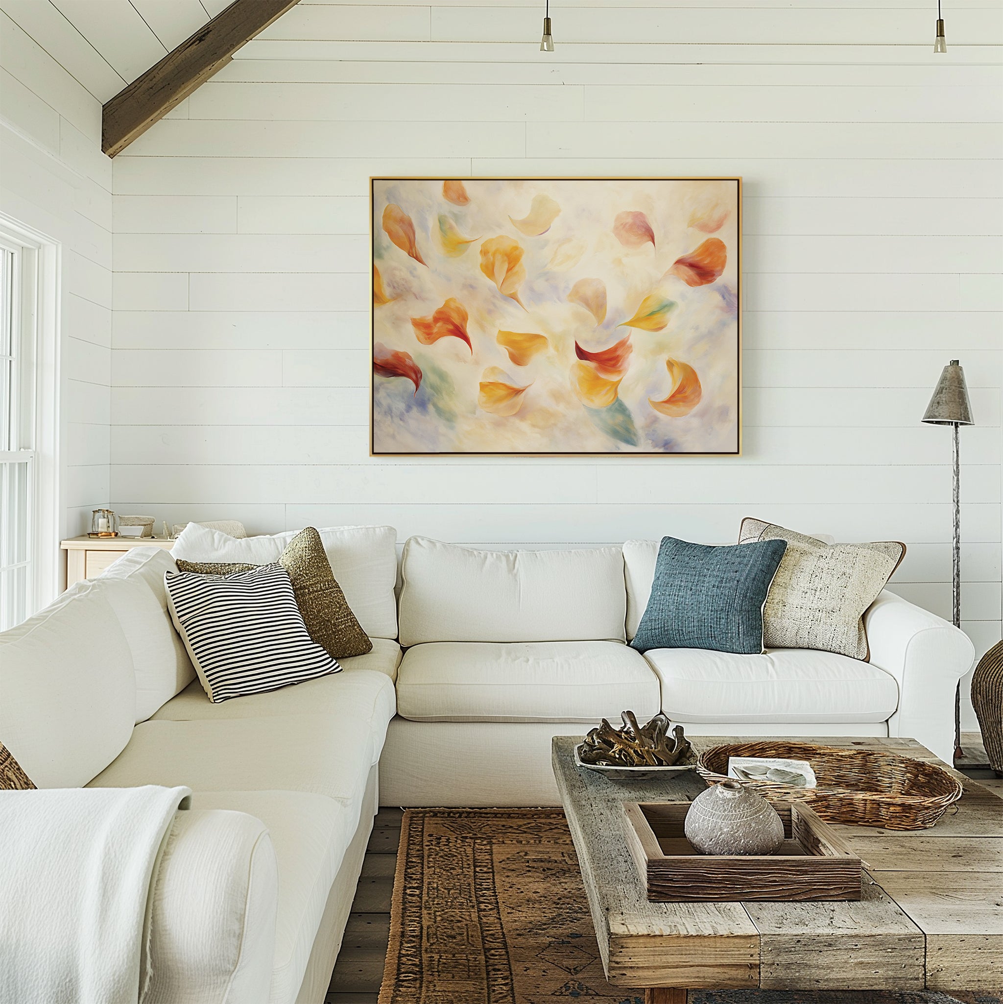 A cozy living room with white shiplap walls, a large white sectional sofa, a rustic wooden coffee table, and the Floating Petals Canvas Art - Horizontal displayed above the couch for an elegant organic touch.