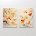 Floating Petals - Set of 2 features canvas paintings with swirling petals in warm yellow, orange, and red on a soft blue-green background. The art exudes organic elegance with an airy, delicate feel.