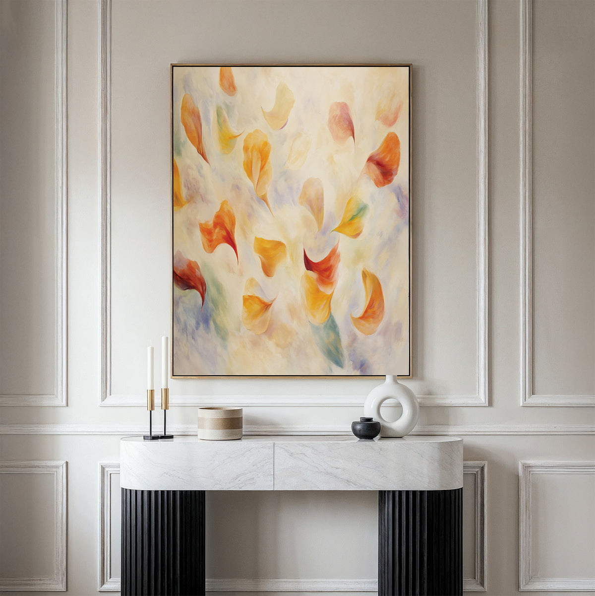 A modern entryway showcases a marble console, decorative objects, and the Floating Petals Canvas Art - Vertical, with its swirling orange, yellow, and blue shapes adding organic elegance to the neutral-toned wall with elegant molding.