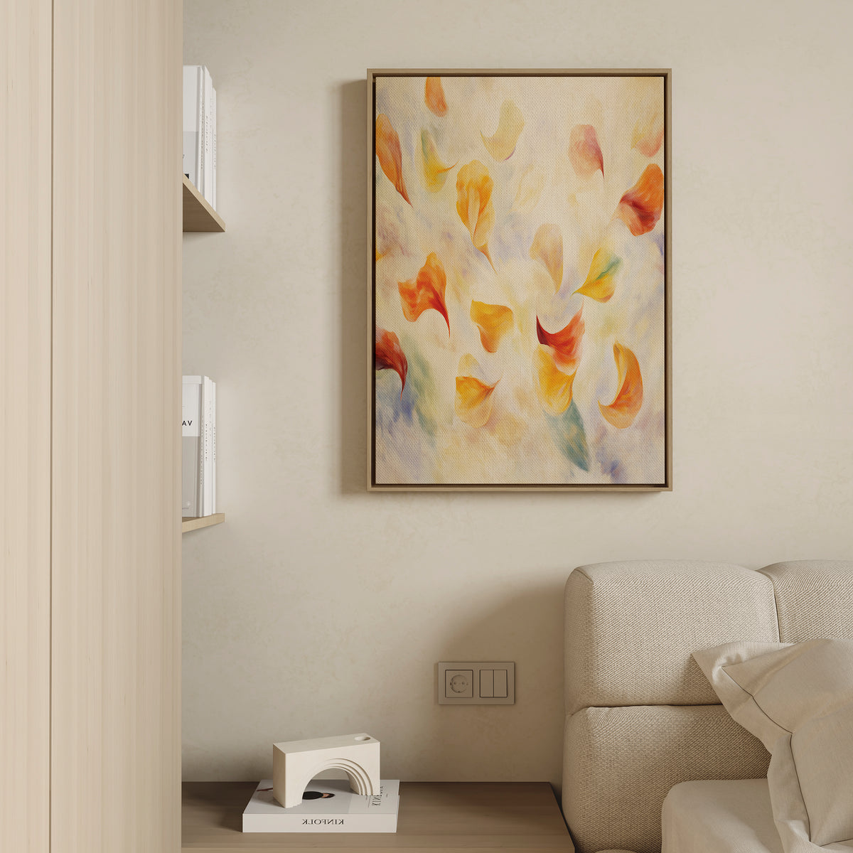 A modern living room corner with a beige sofa, a small shelf with books and a white decorative piece, and the Floating Petals Canvas Art - Vertical featuring colorful abstract orange, yellow, and red brushstrokes for organic elegance.