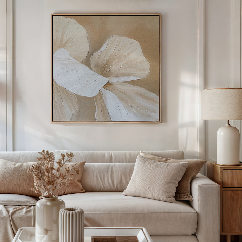 A neutral-toned living room with a beige sofa, tan and cream cushions, a side table with a white lamp, dried flowers in a vase, and the Floral Whisper Abstract Canvas Art in soft beige and white tones on the wall.
