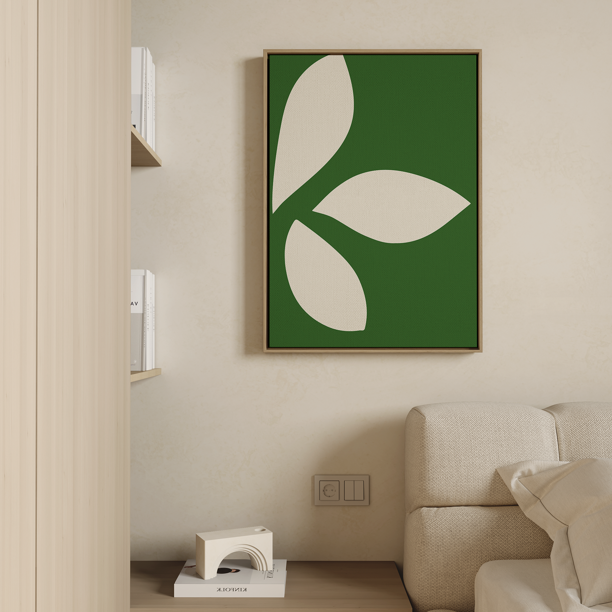 A modern living room corner featuring a beige sofa, wooden shelf with books, and the Leaf Silhouette Abstract Canvas Art—an abstract piece with green framing and cream leaf shapes—brings modern elegance to the decor.