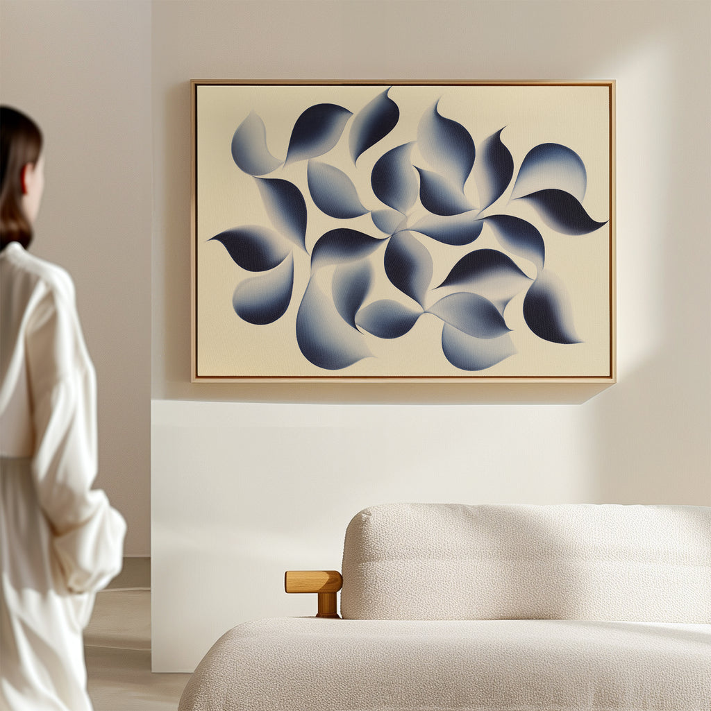A person in a light outfit admires the Flowing Shadows Canvas Art - Horizontal, featuring swirling blue and gray shapes on beige, displayed above a textured sofa in a modern living room.