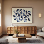 A modern living room with a wooden sideboard, low coffee table, and light sofa features the Flowing Shadows Canvas Art - Horizontal above. A vase with flowers and a book rest on the table; gentle lighting creates a serene atmosphere.