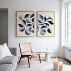 A modern living room with a gray sofa, wooden chair, and small round table. The Flowing Shadows - Set of 2 wall art adds style above, while large windows and candles create a bright, cozy atmosphere.