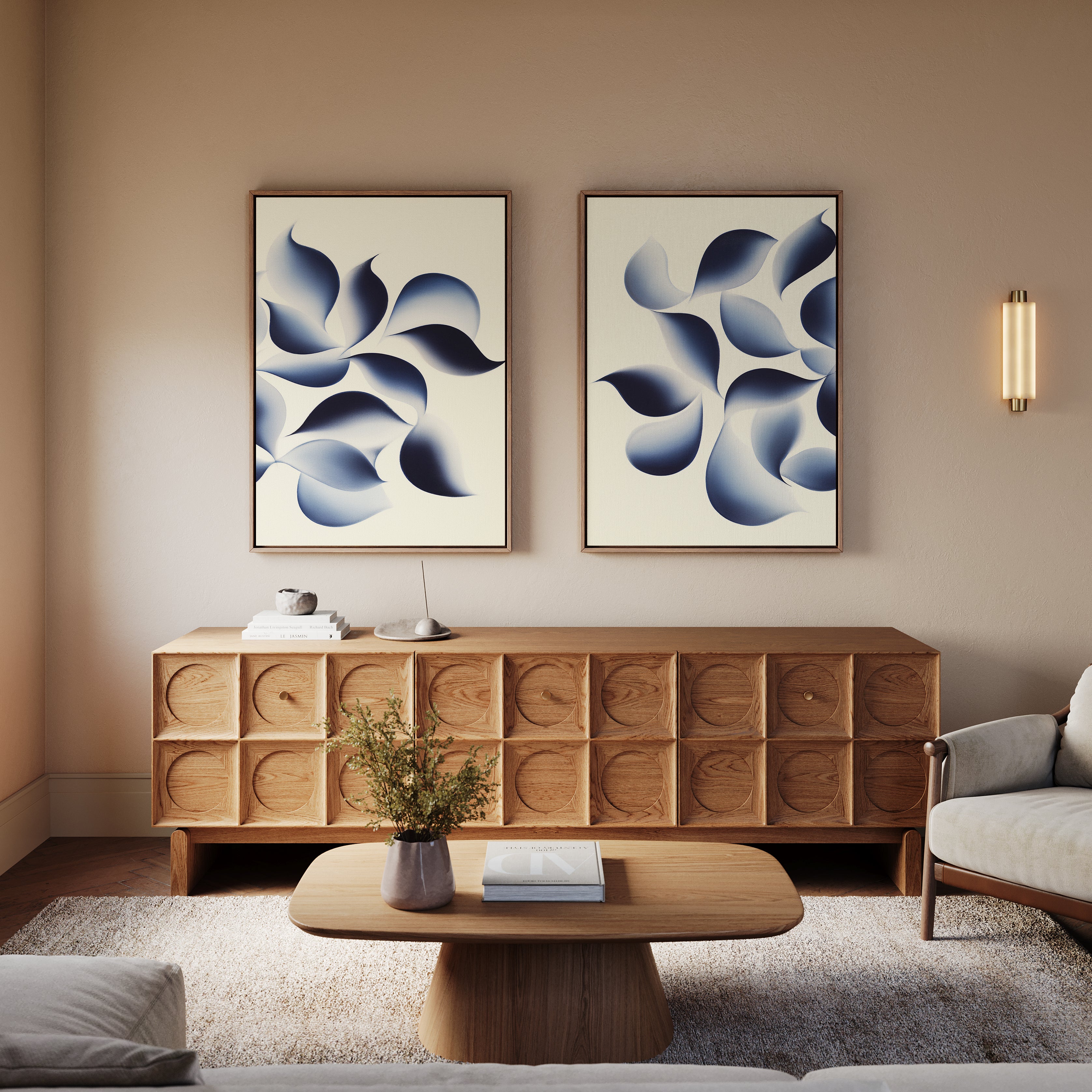 A modern living room features a wooden sideboard, beige sofa, matching coffee table, and "Flowing Shadows - Set of 2" abstract canvas prints above the sideboard. A small plant and books complete the cozy decor.