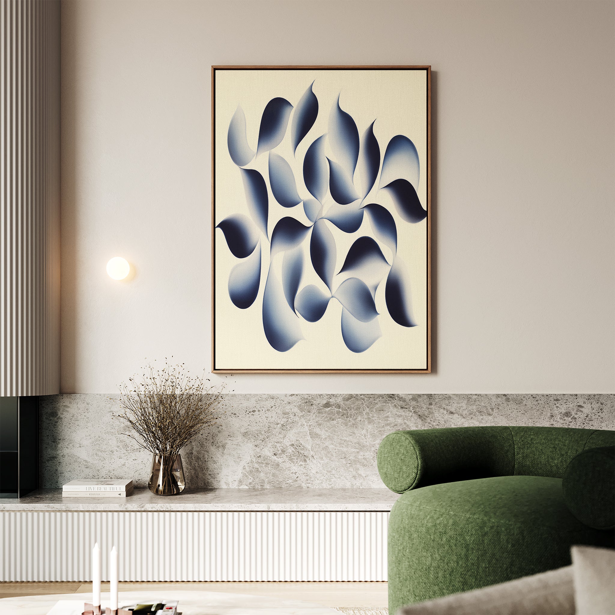 A modern living room showcases the Flowing Shadows Canvas Art - Vertical in blue and white, paired with a green curved sofa, a small vase of dried branches, and minimalist decor in calming neutral tones.