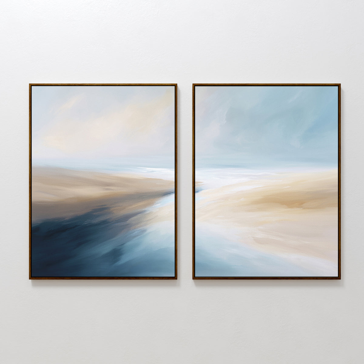 The "Fluid Motion - Set Of 2" features abstract landscape paintings in soft blue, beige, and white tones. This coastal wall art evokes tranquility and is ideal for modern living room decor hung on a white wall.