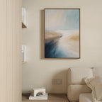 The Fluid Motion Canvas Art - Vertical in soft teal and sandy beige tones hangs on a cream wall above a beige sofa, next to minimalist wood shelves—perfect for modern living room decor.