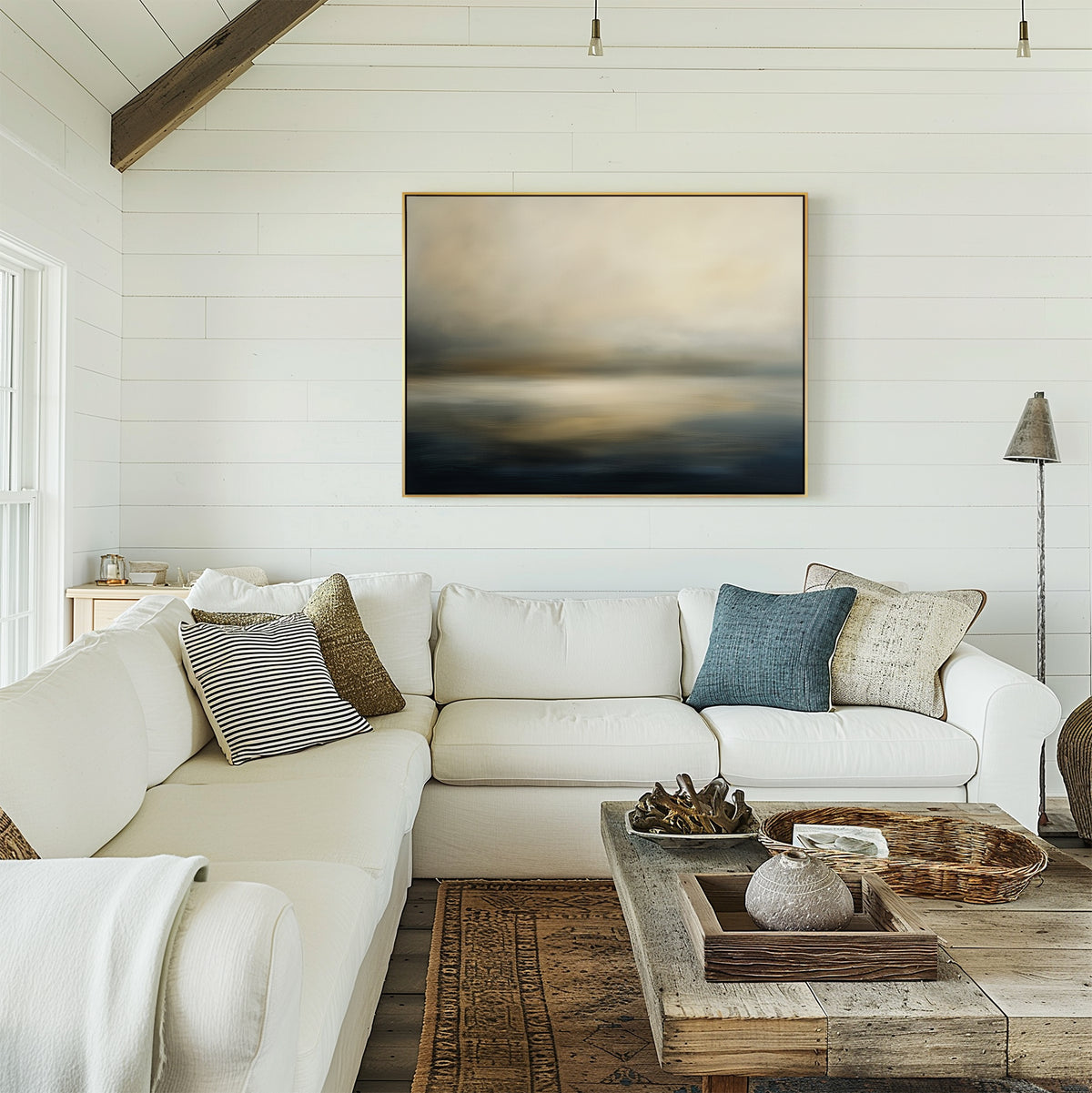 Bright living room with white shiplap walls, a large white sectional sofa, assorted pillows, and a rustic wooden coffee table. The Foggy Bay Impressions Canvas Art - Horizontal above the couch brings serene Nordic Park-inspired decor.