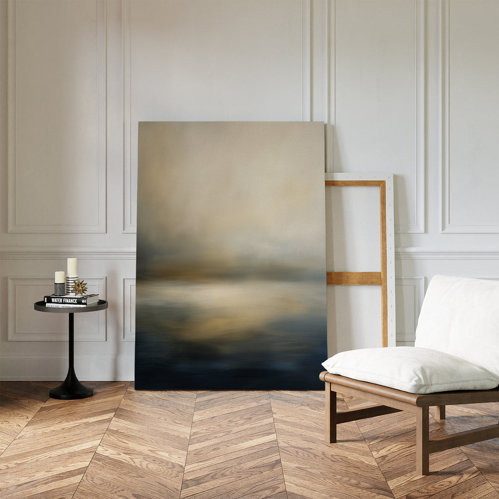 A minimalist room exudes serene elegance with a white cushioned chair, black side table, and the "Foggy Bay Impressions Canvas Art - Vertical" print leaning against a white paneled wall on a wood herringbone floor.