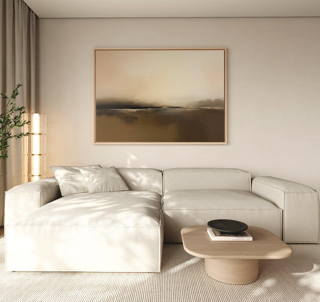 A modern living room with a cream sectional, light wood coffee table, black bowl, floor lamp, potted plant, and the Foggy Beach Expanse Canvas Art - Horizontal adding serene, neutral tones to the beige wall.