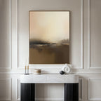 A modern console table with decor accents sits against elegant white paneling, beneath the Foggy Beach Expanse Canvas Art - Vertical in warm beige and brown tones.