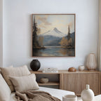 A cozy living room with a beige sofa, neutral pillows, wooden sideboard, and tranquil decor featuring the Frosted Ascent Canvas Art - Square: a framed landscape of snowy mountains above a forest and lake.