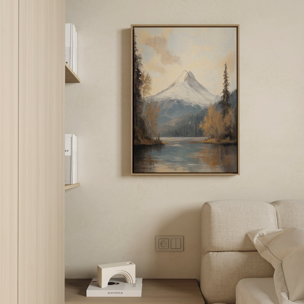 A cozy living room with a beige sofa, a low shelf with books and decor, and tranquil nature vibes—a "Frosted Ascent Canvas Art - Vertical" featuring mountains and a serene lake—hanging above the sofa.