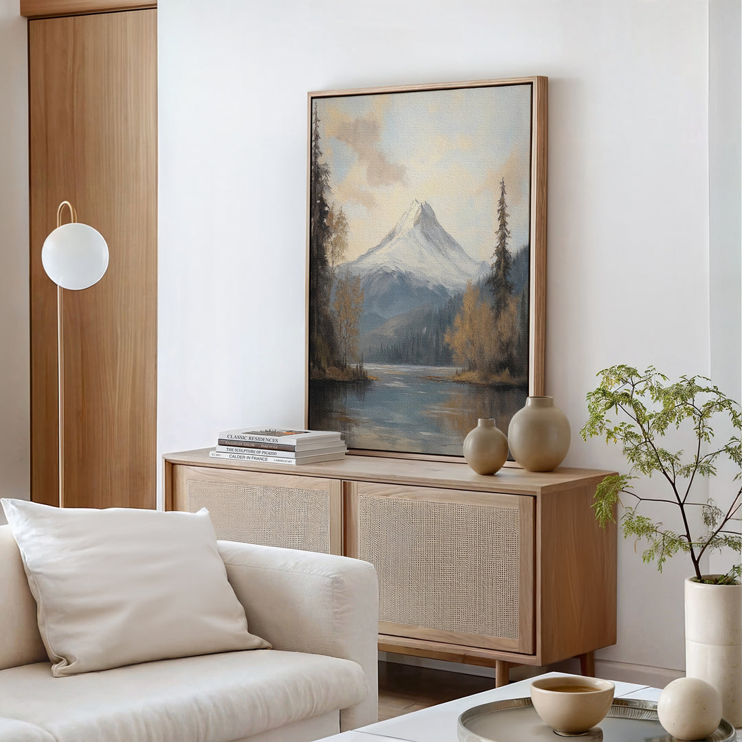 A minimalist living room showcases the Frosted Ascent Canvas Art - Vertical above a light wood sideboard, styled with neutral vases, stacked books, and a small plant next to a white sofa with cream cushions.