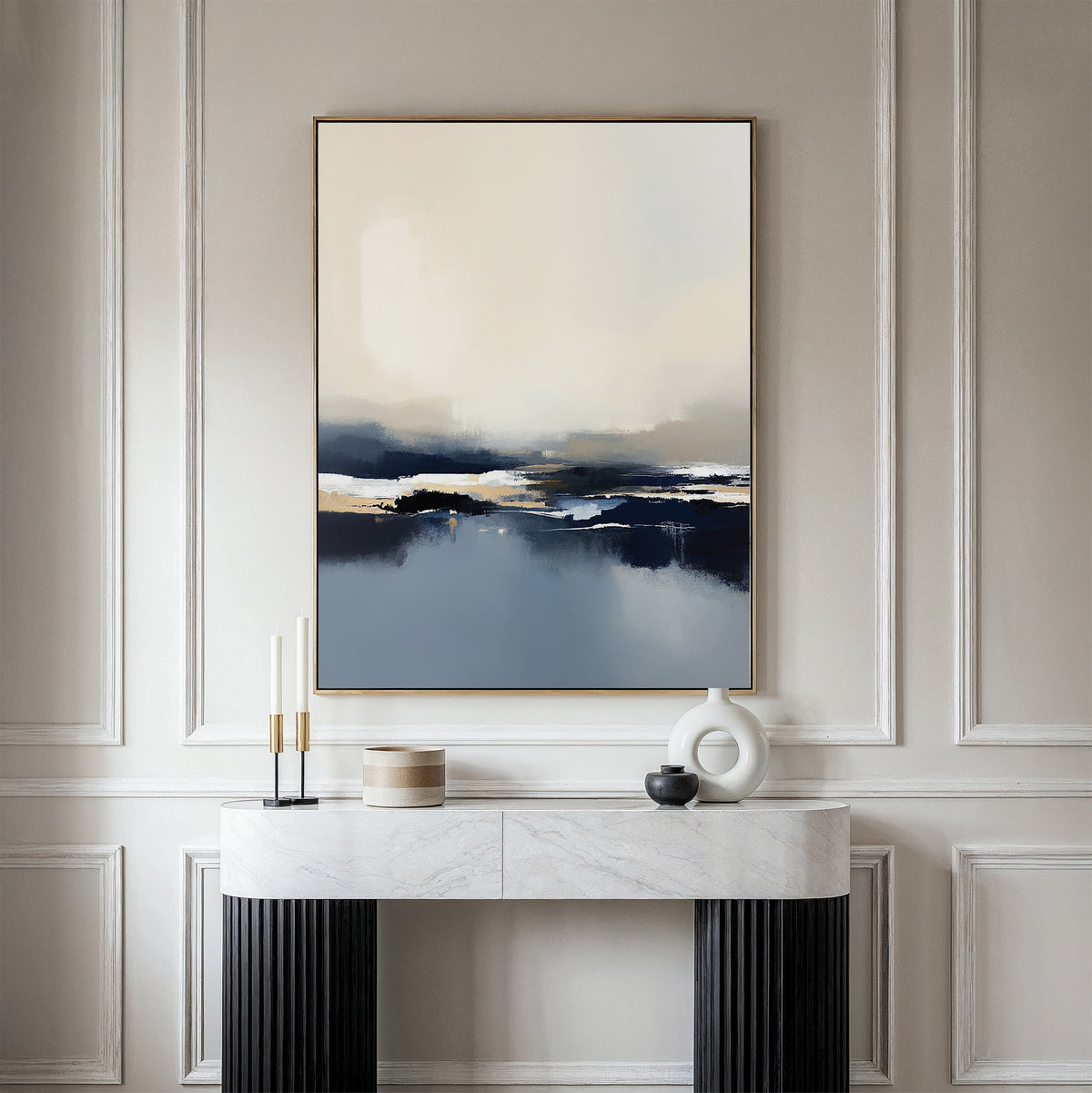 A minimalist room with white paneled walls, a marble console table displaying modern decor, and the Frozen Bay Canvas Art - Vertical—a contemporary blue, beige, and white print—hanging above.