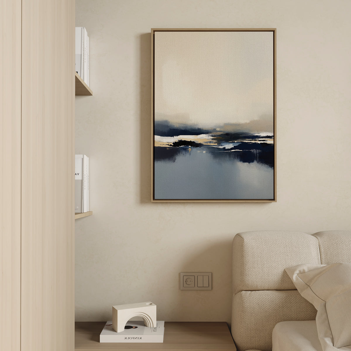 Minimalist living room with a beige sofa, light wood shelving, and the Frozen Bay Canvas Art - Vertical in neutral and blue tones on a cream wall above books and a small geometric decorative piece.